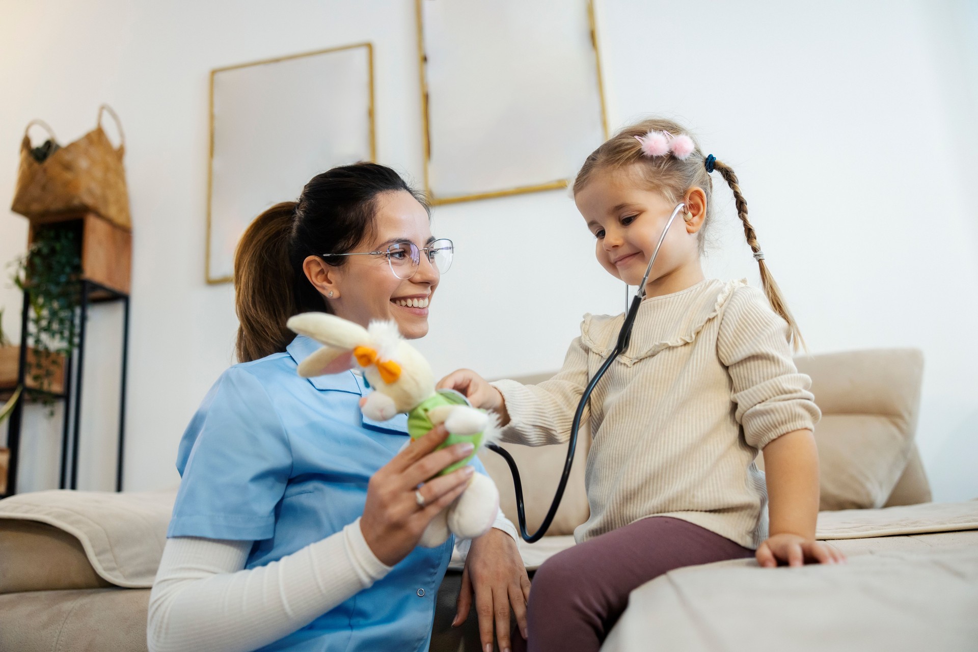 Smiling girl is playing doctor with her pediatrician during doctor home visit.